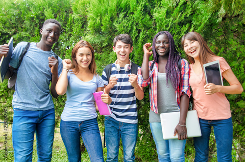 Happy group of african, asian and caucasin teenagers enjoying outdoor time standing in a park