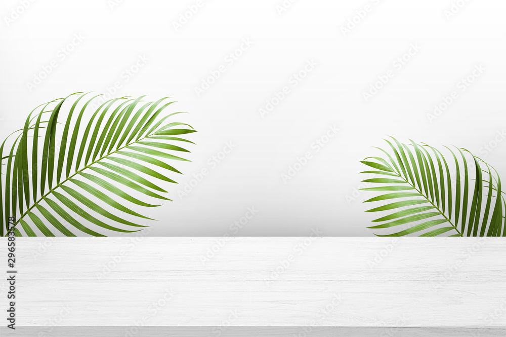 white wooden table top with green palm leave for product advertisement display on white background - obrazy, fototapety, plakaty 