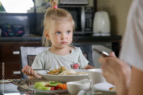 Adorable toddler girl having a meal at the kitchen table
