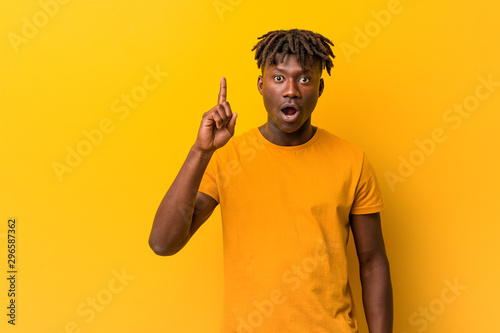 Young black man wearing rastas over yellow background having some great idea, concept of creativity.