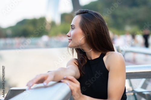 Young pretty likable cheerful woman posing summer city outdoor in Kyiv, Ukraine. Beautiful self-confident girl with long brown hair posing on Dnipro river bank enjoing her life, urban lifestyle