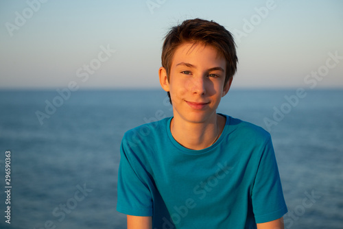 Handsome young boy at beach. Beautiful calm smiling teen boy at Mediterranean sea coast. Travel, summer vacation, tourism, teenage lifestyle. © Khorzhevska