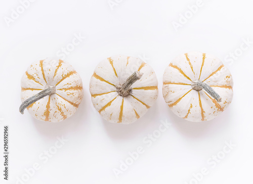 Whole gourds minimal flat lay on white background with copy space, pumpkins in a row, vegetable still life.