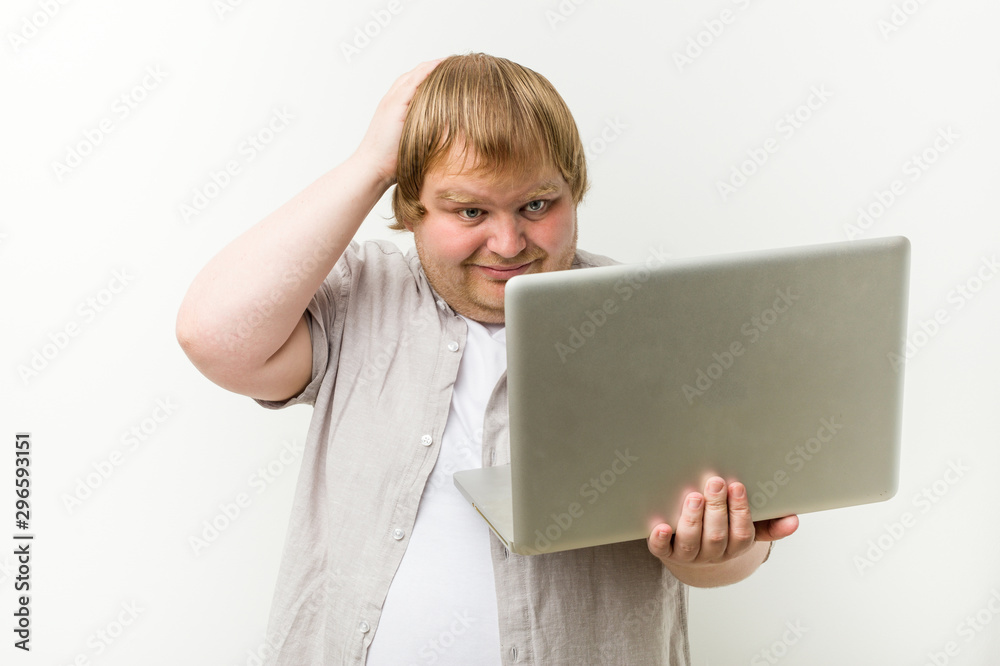 Caucasian plus size man holding a laptop being shocked, she has remembered important meeting. Caucasian plus size man holding a laptop being shocked, she has remembered important meeting.