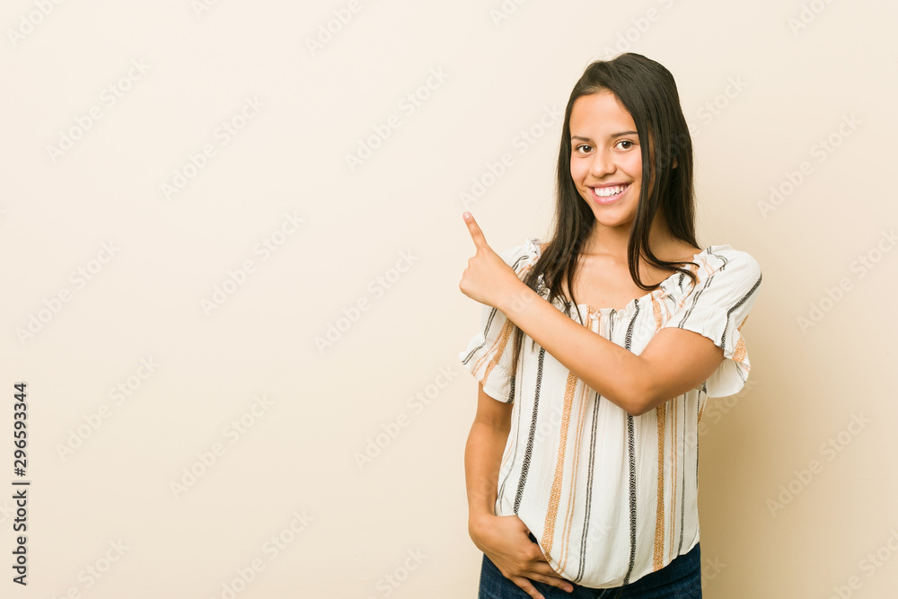 Young hispanic woman smiling and pointing aside, showing something at blank space. Young hispanic woman smiling and pointing aside, showing something at blank space.