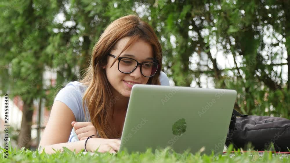 Caucasian girl lying on the grass using laptop. Slow motion Caucasian girl lying on the grass using laptop. Slow motion