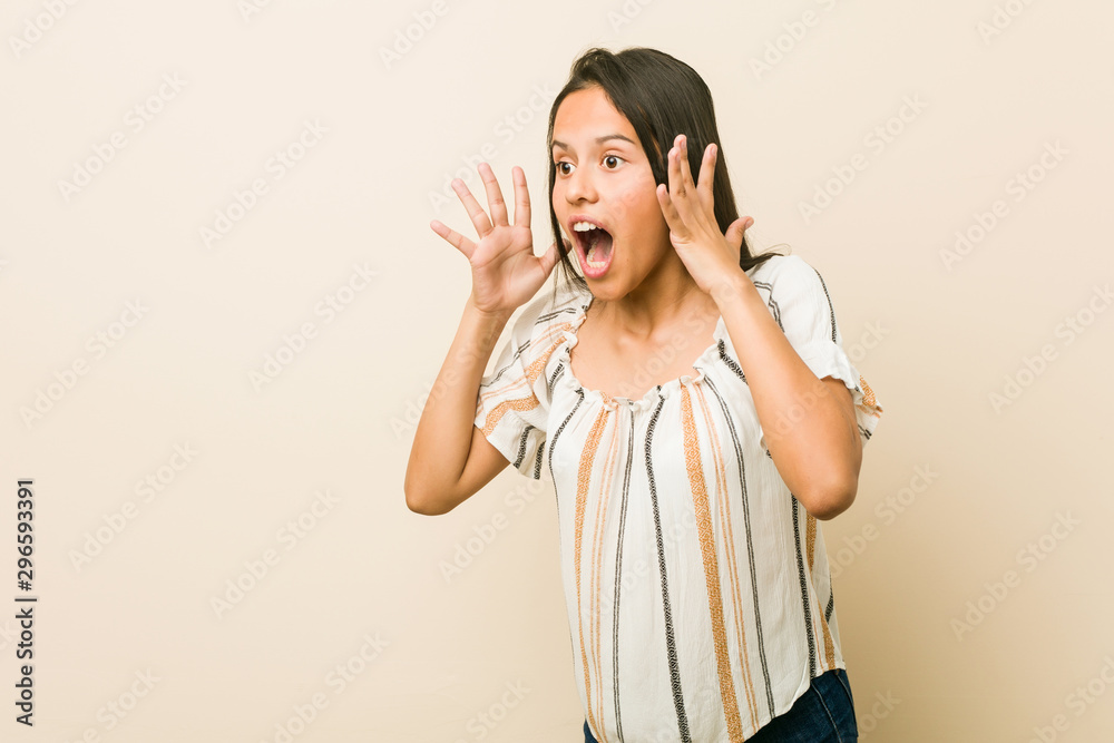 Young hispanic woman shouts loud, keeps eyes opened and hands tense. Young hispanic woman shouts loud, keeps eyes opened and hands tense.