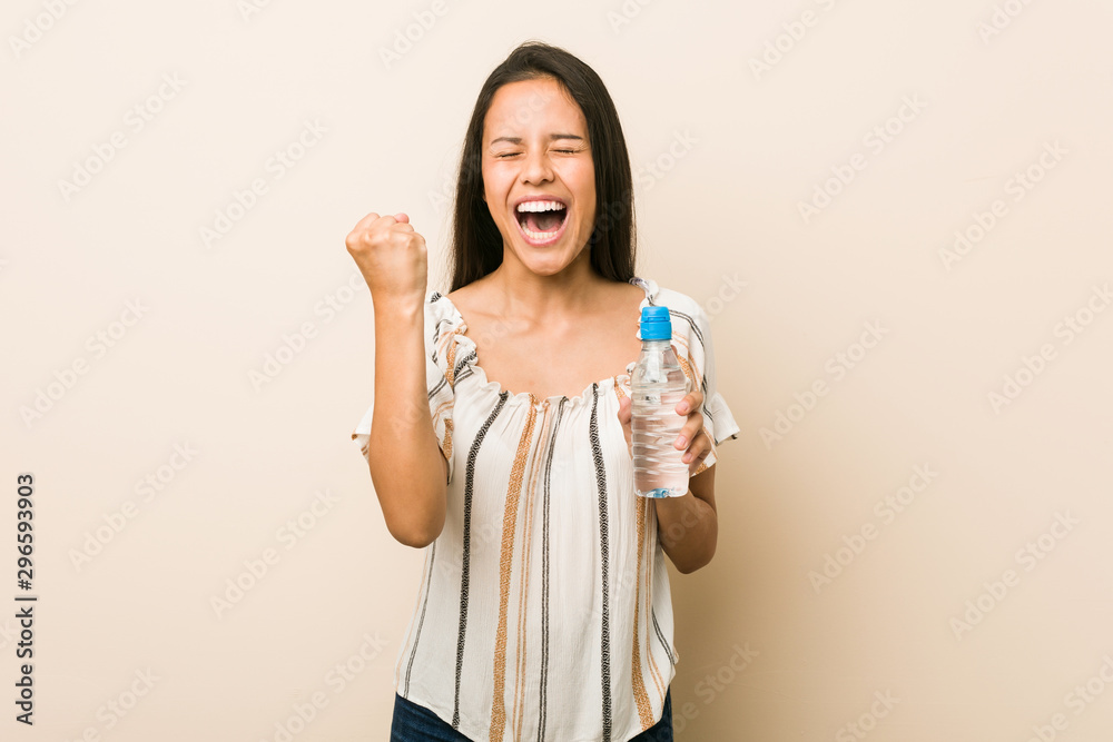 Young hispanic woman holding a bottle of water cheering carefree and excited. Victory concept. Young hispanic woman holding a bottle of water cheering carefree and excited. Victory concept.