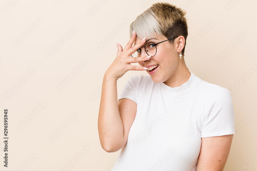 Young authentic natural woman wearing a white shirt blink at the camera through fingers, embarrassed covering face. Young authentic natural woman wearing a white shirt blink at the camera through fingers, embarrassed covering face.