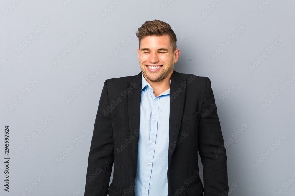 Young handsome caucasian man laughs and closes eyes, feels relaxed and happy.