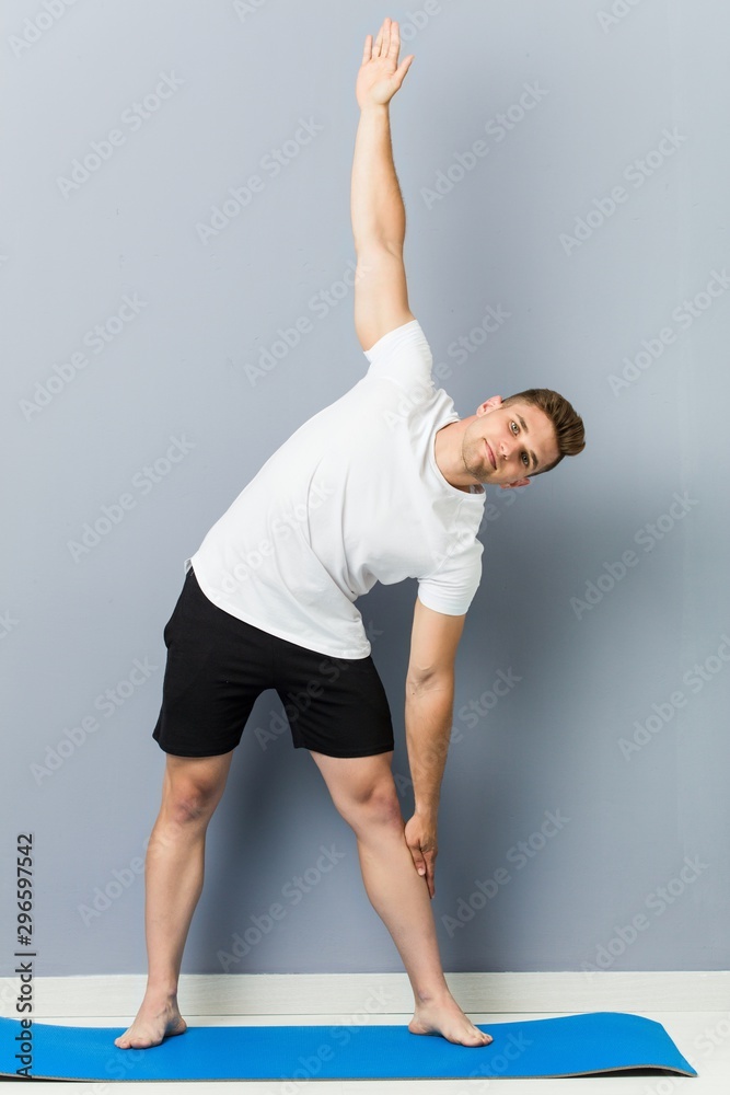 Naklejka premium Young caucasian man practicing yoga indoor