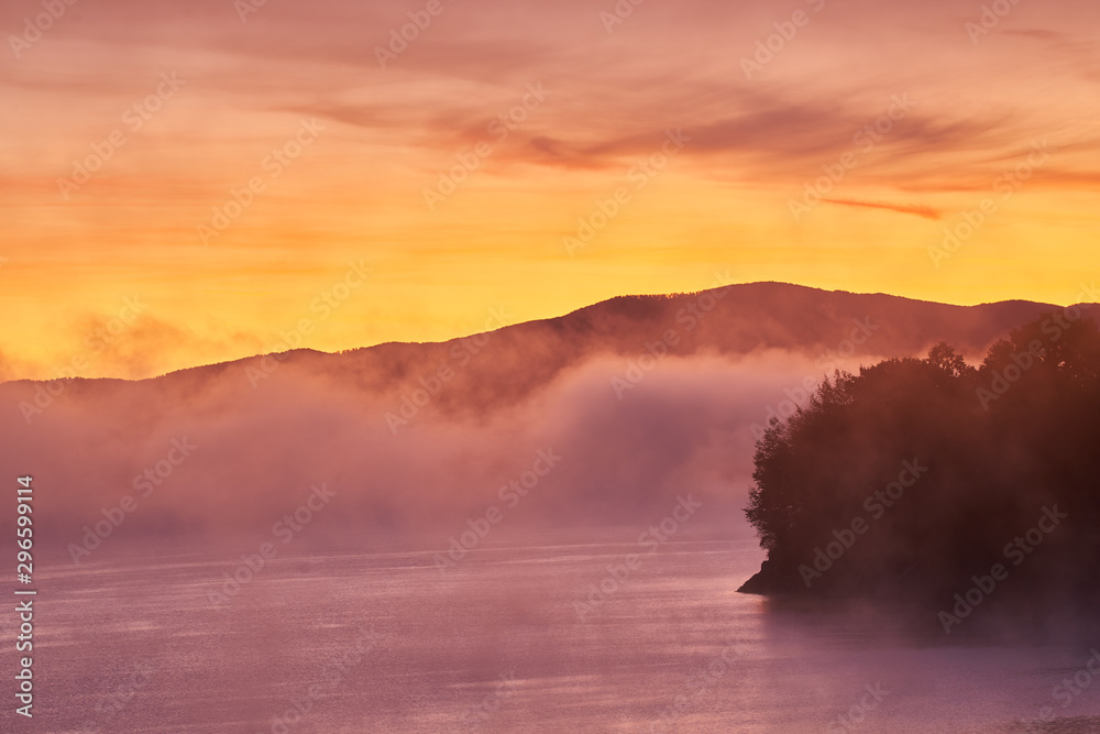 The dawn stories of the lake. A beautiful view of the mountain with fog and lake in the foreground.