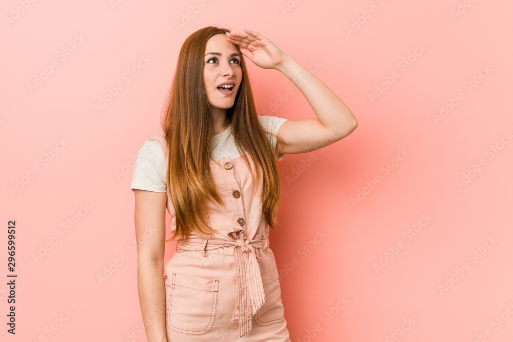 Young ginger woman with freckles looking far away keeping hand on forehead. Young ginger woman with freckles looking far away keeping hand on forehead.