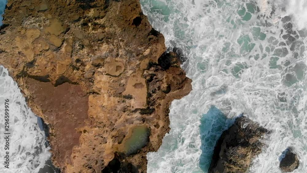 Rocks against ocean waves, overhead super slow motion view from drone Rocks against ocean waves, overhead super slow motion view from drone