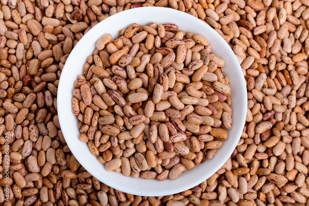 Read bean beans in a white bowl and around on a table in warm light, top view Read bean beans in a white bowl and around on a table in warm light, top view
