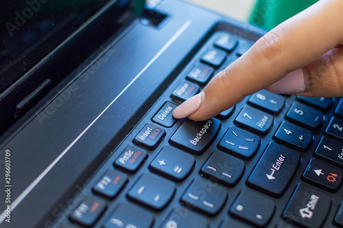 finger pushing delete button on a keyboard of computer