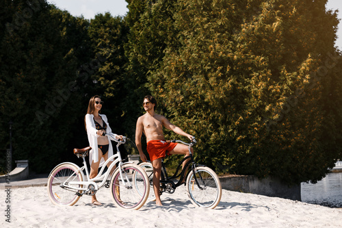 A couple enjoying a day at the beach riding a tandem bike.