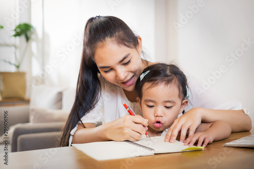 Young Asian beautiful mom with her dougther kid work at home.