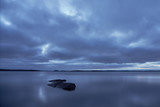 Rocks in water of a lake on twilight under cloudy sky. Copy space. 