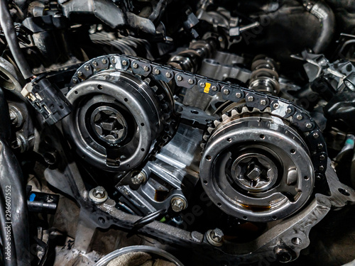 Close-up on a disassembled engine with a view of the gas distribution mechanism, chain, gears and tensioners during repair and restoration after a breakdown. Auto service industry.