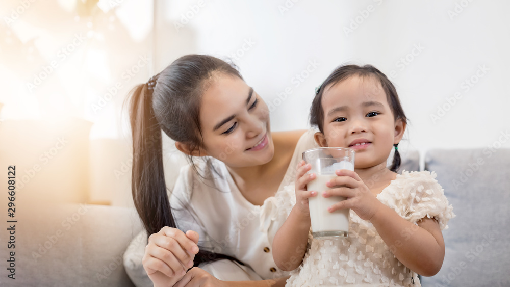 Young happy Asian mother and daughter coloring together at home with art tools and a glass of milk. Young happy Asian mother and daughter coloring together at home with art tools and a glass of milk.