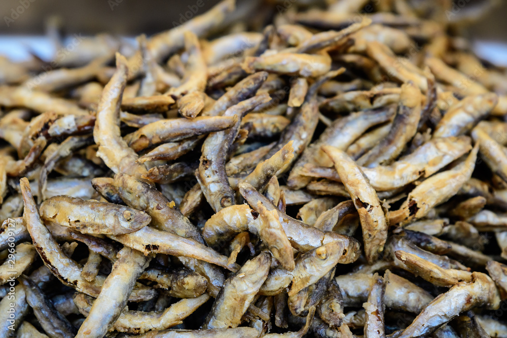 Large group of deep fried little anchovies in display at a street food market ready to eat seafood, photographed with soft focus