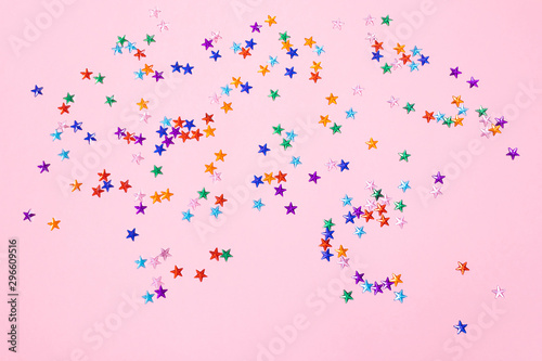 Multi-colored rhinestones in the form of stars on a pastel pink background. The concept of a holiday, party, birthday. Minimalism. Copy space.