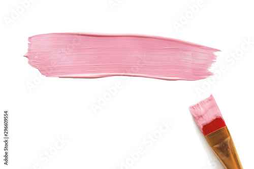 A brushstroke of pink acrylic paint and a paint brush next to it. Isolate on a white background...