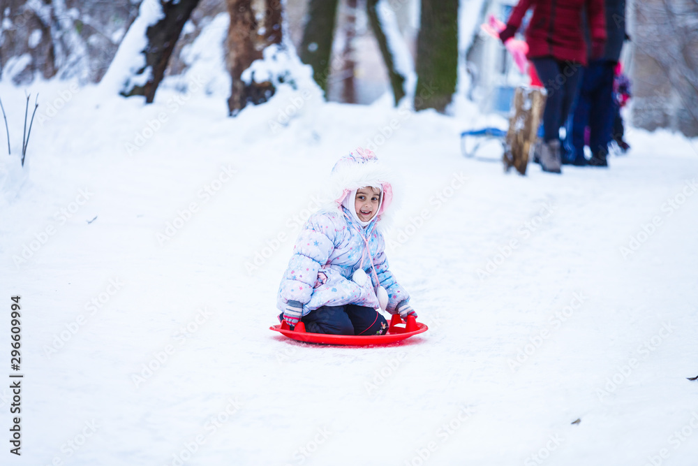 Cute litter girl sliding down on the snow mountain