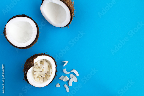 Coconut halves and chips on the blue background. Top view. Copy space. Tropical background.