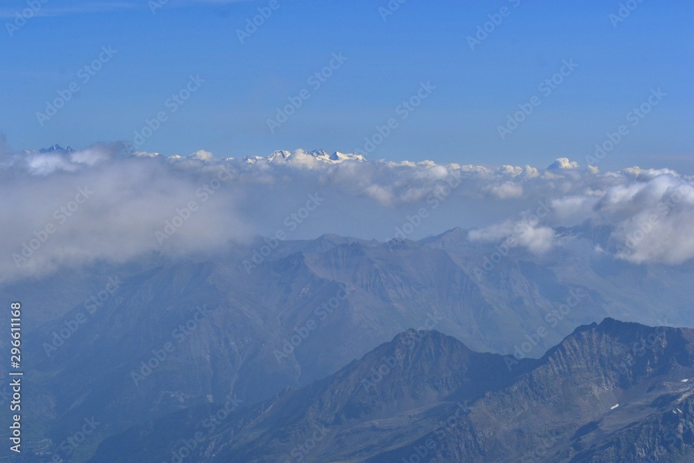 Mont Blanc from the top of Gran Paradiso mountain. High mountains, white clouds mountain range covered with snow in the distance. Sunny day.