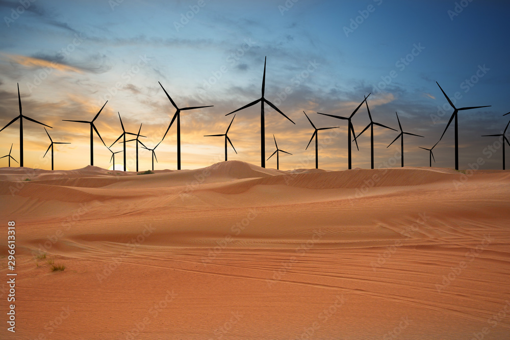 Wind turbines in the desert suggesting renewable energy concept with sand dunes at sunset