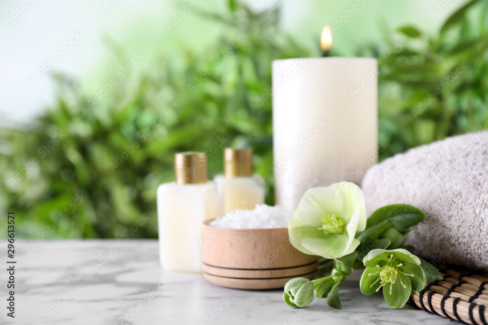 Composition with flowers, sea salt and towel on white marble table against blurred background, space for text. Spa concept Composition with flowers, sea salt and towel on white marble table against blurred background, space for text. Spa concept