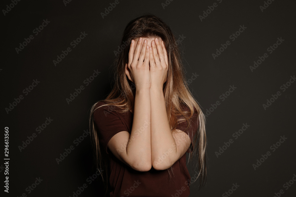 Upset young woman crying against dark background Upset young woman crying against dark background