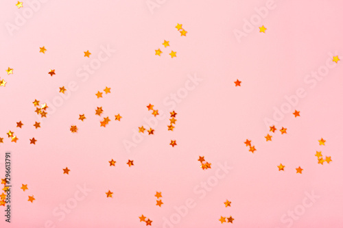 Pink background with golden stars, copy space. Golden stars confetti on pastel background.