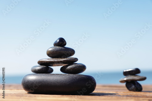 Stacks of stones on wooden pier near sea  space for text. Zen concept