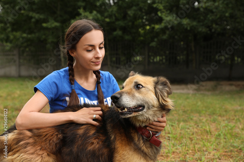 Female volunteer with homeless dog at animal shelter outdoors © New Africa