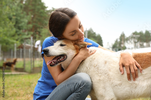 Murais de parede Female volunteer with homeless dog at animal shelter outdoors
