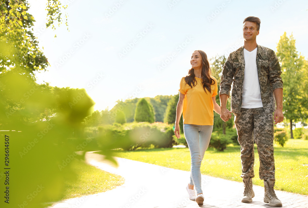 Man in military uniform walking with his girlfriend at sunny park Man in military uniform walking with his girlfriend at sunny park