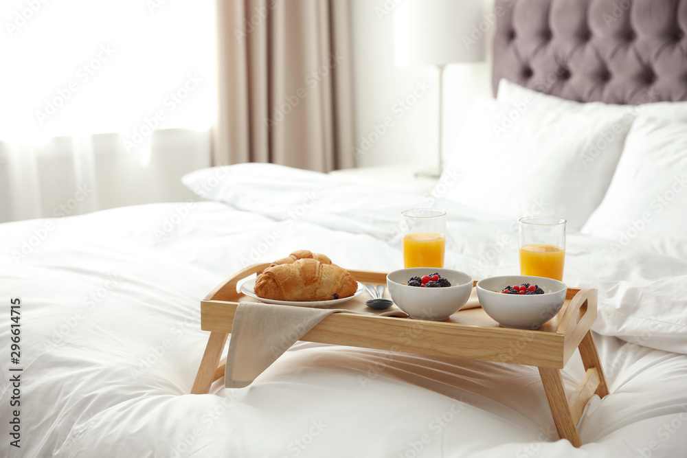 Tray with tasty breakfast on bed in light room - obrazy, fototapety, plakaty 