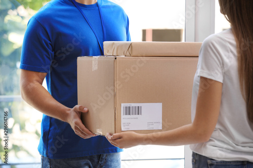 Woman receiving parcels from courier on doorstep, closeup © New Africa