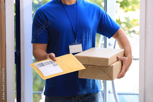 Young courier delivering parcels on doorstep, closeup