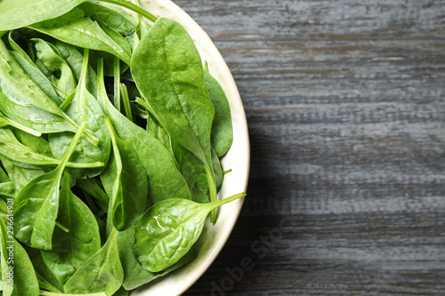 Fresh green healthy spinach on dark wooden table, top view. Space for text