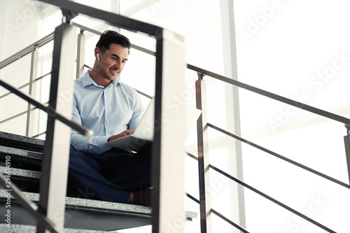 Portrait of young man with laptop indoors