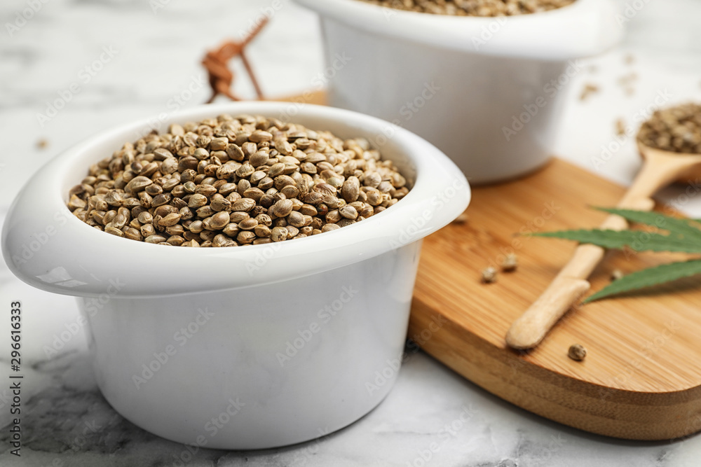 Organic hemp seeds in bowl on marble table Organic hemp seeds in bowl on marble table