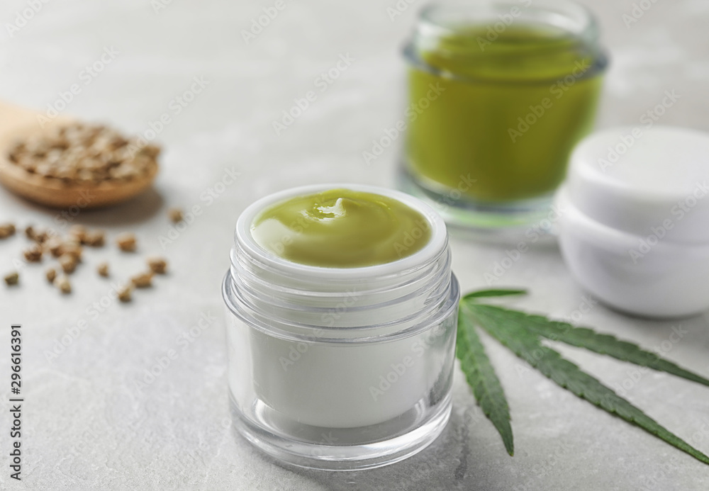 Jars of hemp cream and seeds on grey table. Organic cosmetics