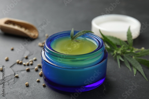 Jar of hemp cream on dark stone table  closeup. Organic cosmetics