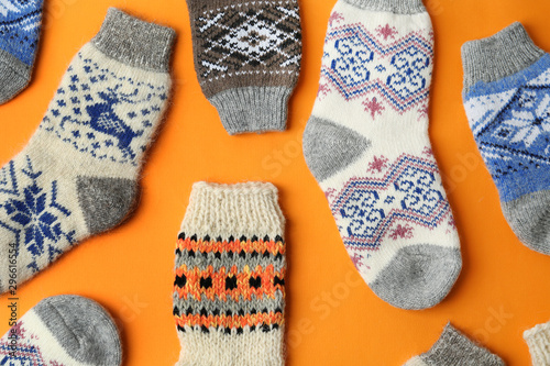 Different knitted socks on orange background, flat lay. Winter clothes