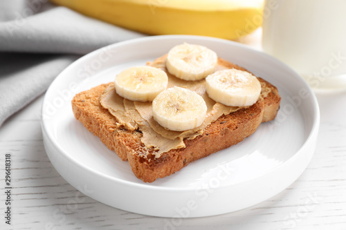 Toast with peanut butter and banana on white wooden table, closeup. Healthy breakfast