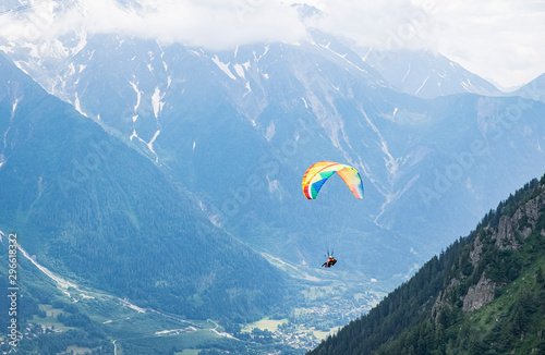 Colorful parachute with two persons gliding between mountains in Chamonix
